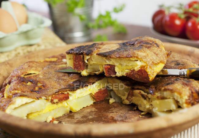 Spanish omelette with chorizo, one slice cut on wooden desk — Stock Photo