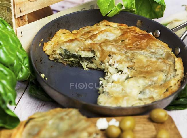 Spanakopita spinach pasty on black pan over table — Stock Photo