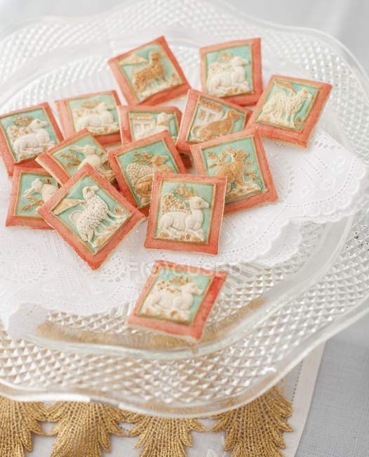 Closeup view of painted Springerle cookies with doily on glass stand — Stock Photo