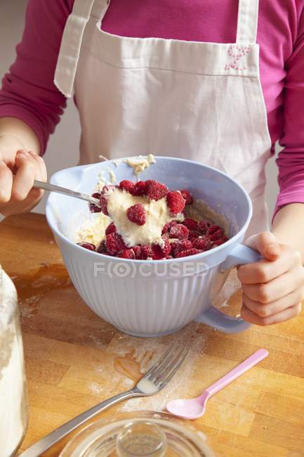 Closeup cropped view of person mixing raspberries with cream in bowl — Stock Photo