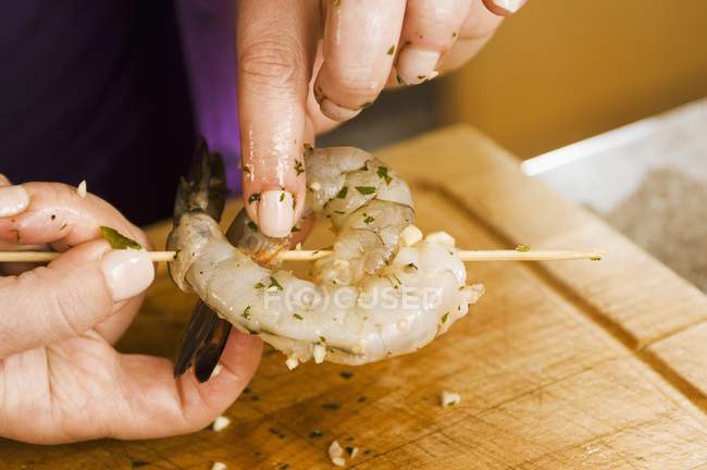 Primo piano vista ritagliata delle mani spiedino gamberetti marinati — Foto stock