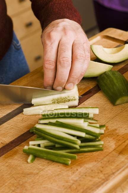 Les mains masculines tranchant le concombre — Photo de stock