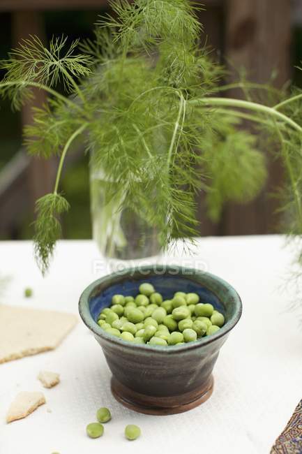 Peas in bowl and dill in glass — Stock Photo