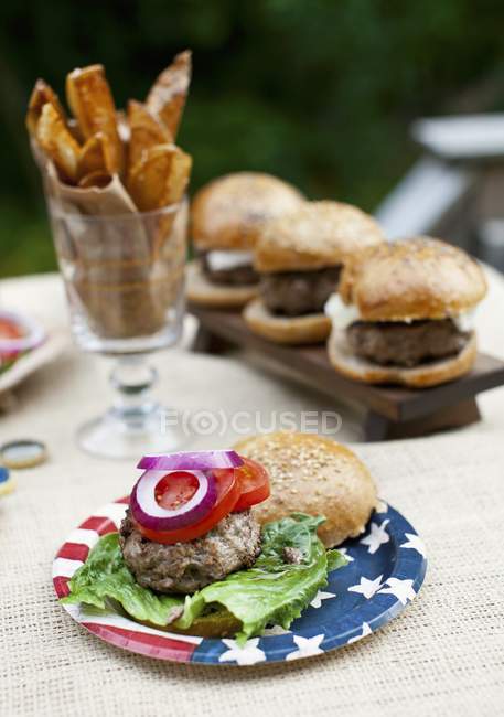Vista elevada de hamburguesas de búfalo a la parrilla en bollos integrales sobre una mesa al aire libre - foto de stock