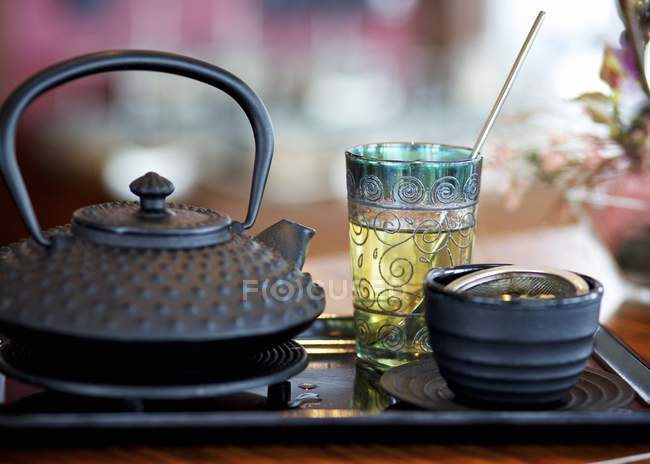 Vue rapprochée de la nature morte avec thé, théière noire et tasse — Photo de stock