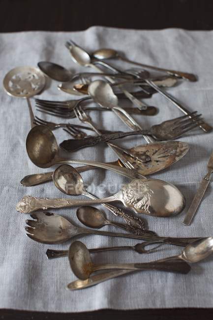 Vista elevada de cucharas viejas y tenedores sobre tela de lino - foto de stock