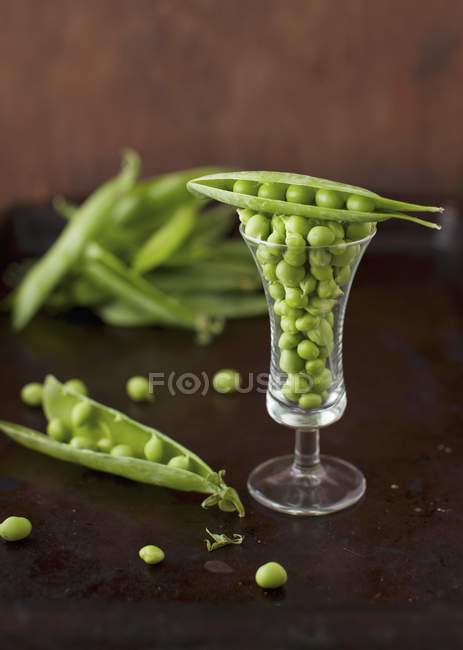 Grüne Erbsen und Schoten im Glas — Stockfoto