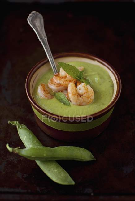 Un bol de soupe de pois verts et menthe avec des crevettes sur fond noir — Photo de stock