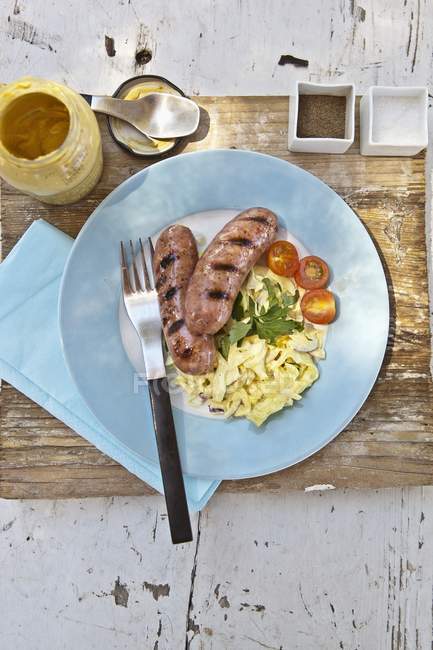 Top view of grilled Bratwurst sausages with white cabbage salad — Stock Photo