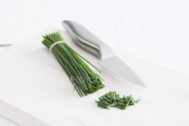 Mazzo di erba cipollina fresca e coltello — Foto stock