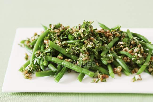 Green beans with walnut pesto  on white plate — Stock Photo