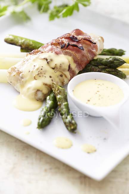 Hake wrapped in bacon with asparagus — Stock Photo