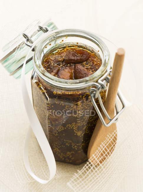 Closeup view of fig Chutney in jar with spoon and ribbon — Stock Photo