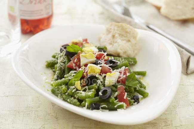 Bohnensalat mit Oliven, Tomaten und Ei auf weißem Teller — Stockfoto
