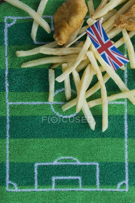 Peixes e batatas fritas (Inglaterra) com uma bandeira Union Jack de papel e decoração temática de futebol — Fotografia de Stock