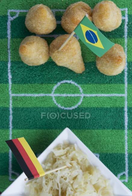 Salgadinhos (Brazil) and sauerkraut (Germany) with football-themed decoration — Stock Photo
