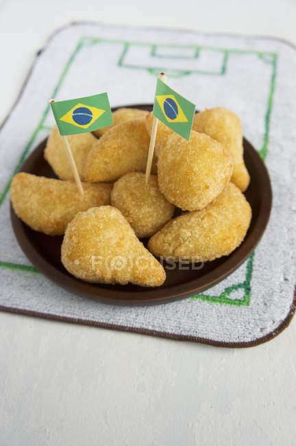 Vista de cerca de los pasteles rellenos de Salgadinhos con decoración temática de fútbol y bandera brasileña - foto de stock