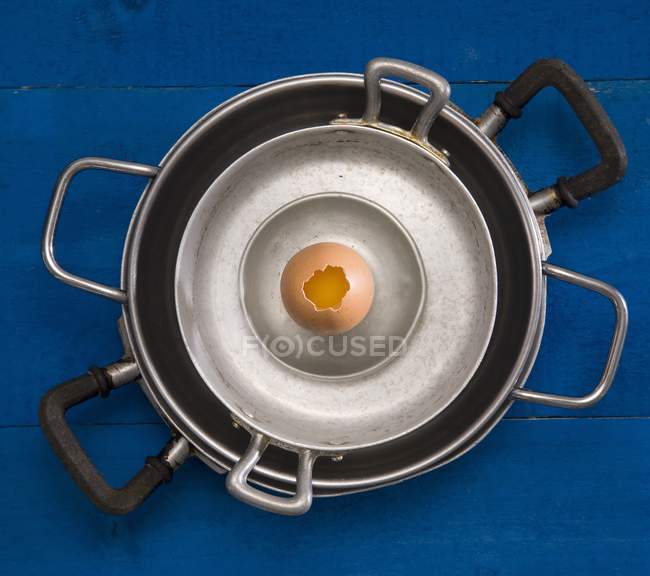 Top view of stacked cookware with a soft-boiled cracked egg in the shell — Stock Photo