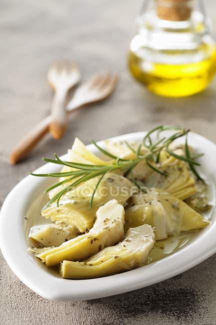 Preserved artichoke hearts with rosemary on white plate — Stock Photo