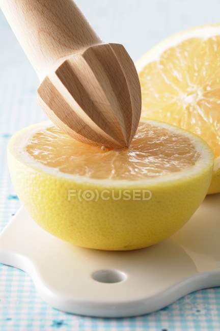 Halved grapefruit with wooden squeezer — Stock Photo