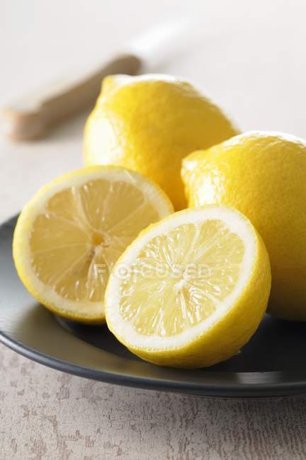 Citrons frais avec moitiés dans une assiette — Photo de stock