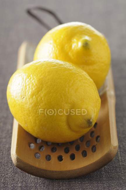Limones frescos en rallador de madera - foto de stock