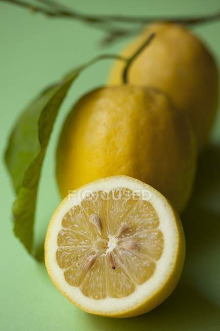 Limones con la mitad y hojas - foto de stock