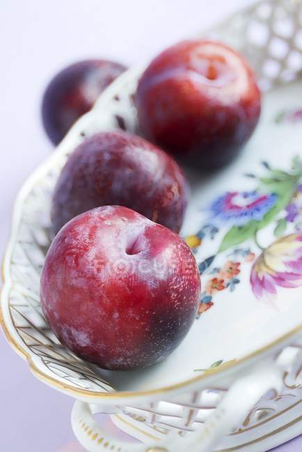 Plums in vintage porcelain dish — Stock Photo