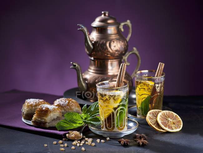 Closeup view of Eastern-style tea with mint, cinnamon, orange and baklava — Stock Photo