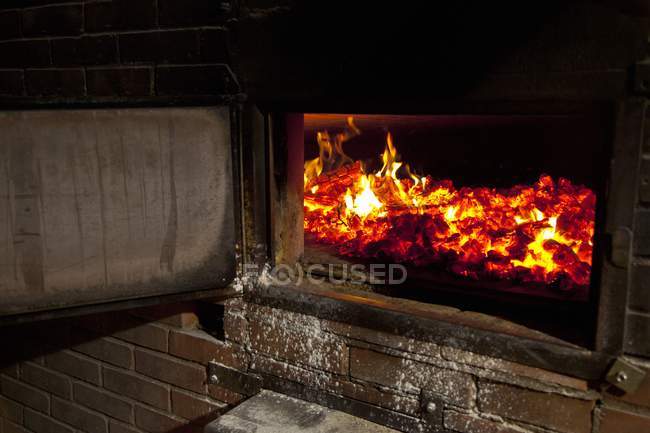 Fogo em um forno a lenha aberto dentro de casa — Fotografia de Stock