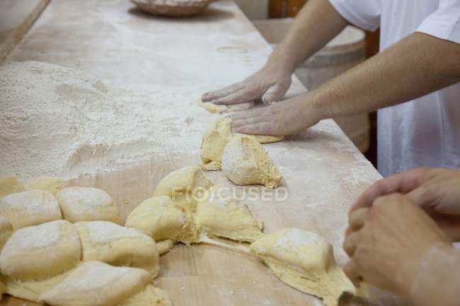 Panaderos moldeando rollos - foto de stock