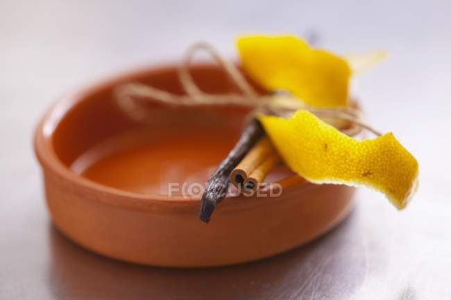 Vue rapprochée de la peau de citron avec bâton de cannelle et gousse de vanille sur ramequin — Photo de stock