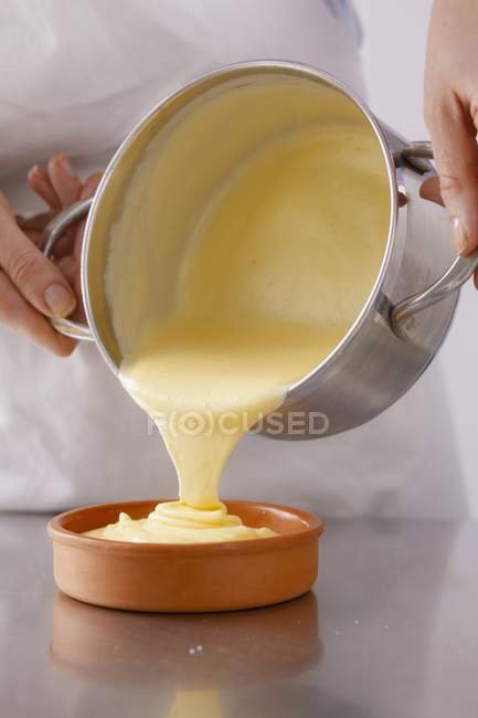 Vue recadrée de la personne versant de la crème du pot au bol — Photo de stock