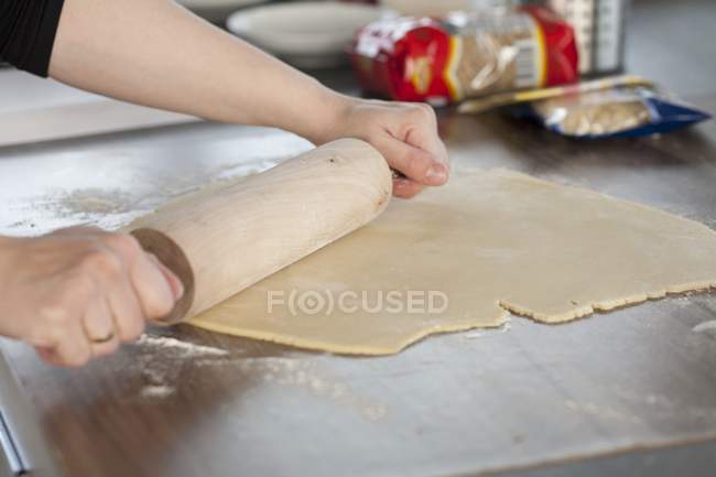 Closeup view of person rolling dough with a rolling pin — Stock Photo
