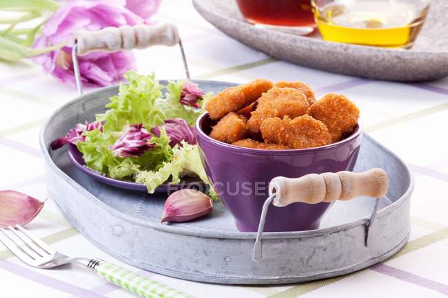 Крупним планом курячі нагетси з салатом і зубчиком часнику на лотку — стокове фото
