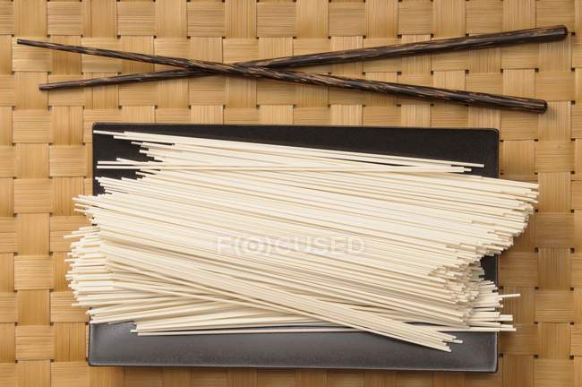 Fideos de arroz crudo en bandeja negra - foto de stock