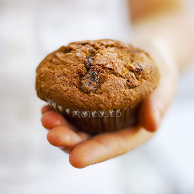 Main tenant muffin aux raisins secs — Photo de stock
