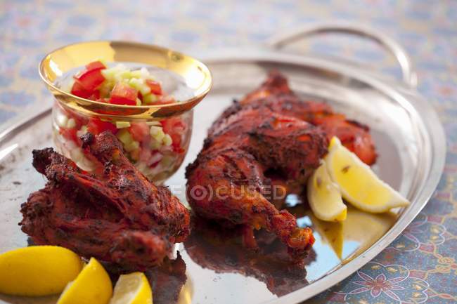 Closeup view of chicken Tikka pieces with vegetable salad and lemon wedges — Stock Photo