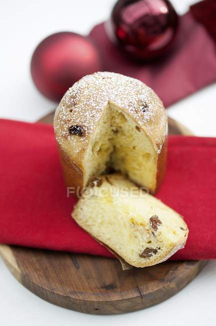 Closeup view of cut Panettone pie with sugar icing on red cloth — Stock Photo