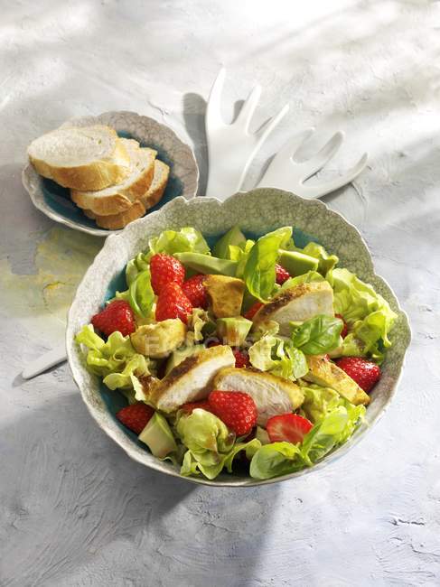 Lettuce with avocado, chicken breast and strawberries in bowl over wooden surface — Stock Photo