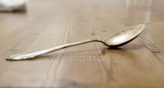 Closeup view of a silver spoon on a wooden surface — Stock Photo