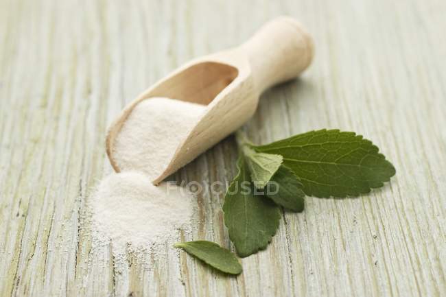Vista da vicino delle foglie di Stevia e della polvere con uno scoop sulla superficie di legno — Foto stock