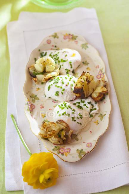 Ovos escalfados com cebolinha e cebola grelhada em prato sobre toalha — Fotografia de Stock