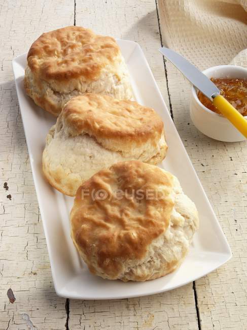 Closeup view of biscuits on plate with jam and knife — Stock Photo