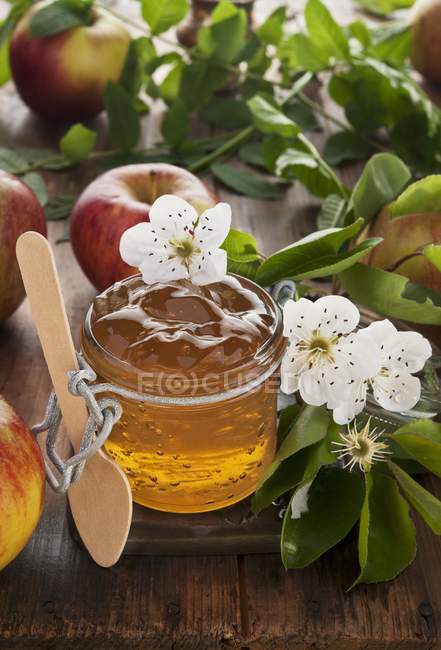 Glass jar of apple jelly with wooden spoon — Stock Photo