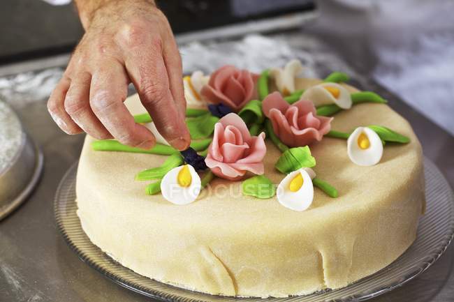 Confectioner decorating marzipan layer cake — Stock Photo
