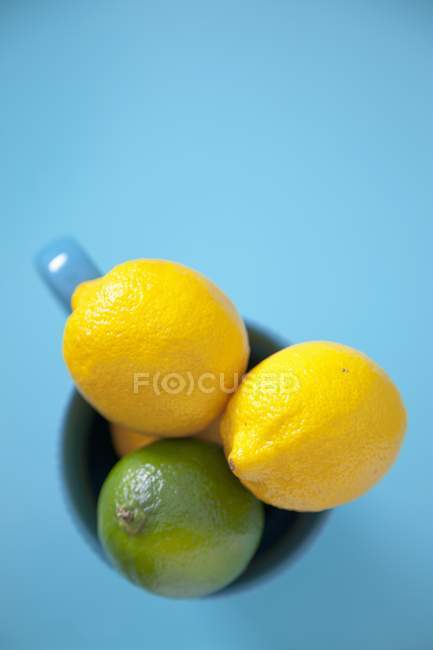 Limones y lima en taza - foto de stock