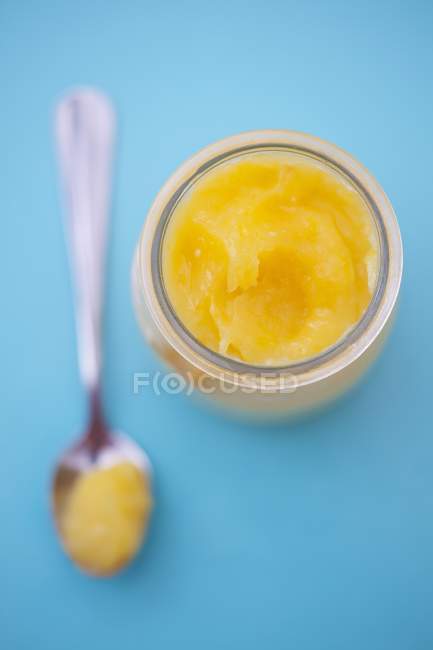 Closeup top view of lemon curd in a jar and on a spoon — Stock Photo