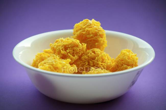 Крупный план гнезд сладкого яичного желтка в белой миске на фиолетовой поверхности — стоковое фото