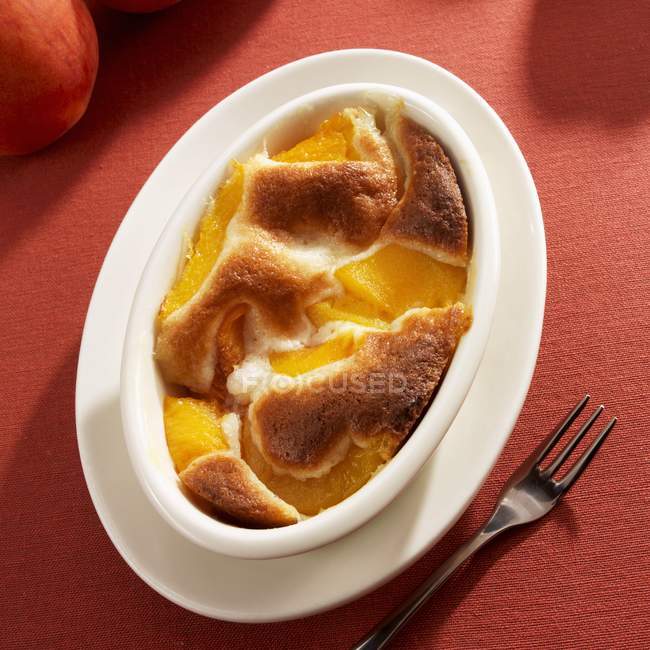 Крупный план персикового пирога в овальной выпечке — стоковое фото